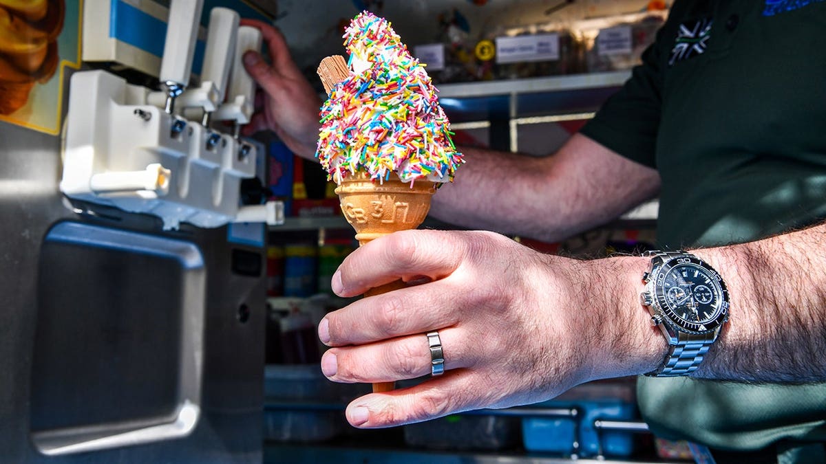 James Shemmeld standing next to an ice cream van holding an ice cream cone with sprinkles