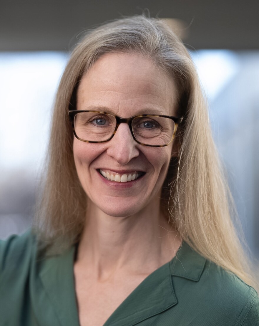 A headshot of Professor Kara Zivin, wearing glasses and a green collared shirt and smiling.