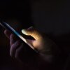 a hand holding a smart phone in the dark