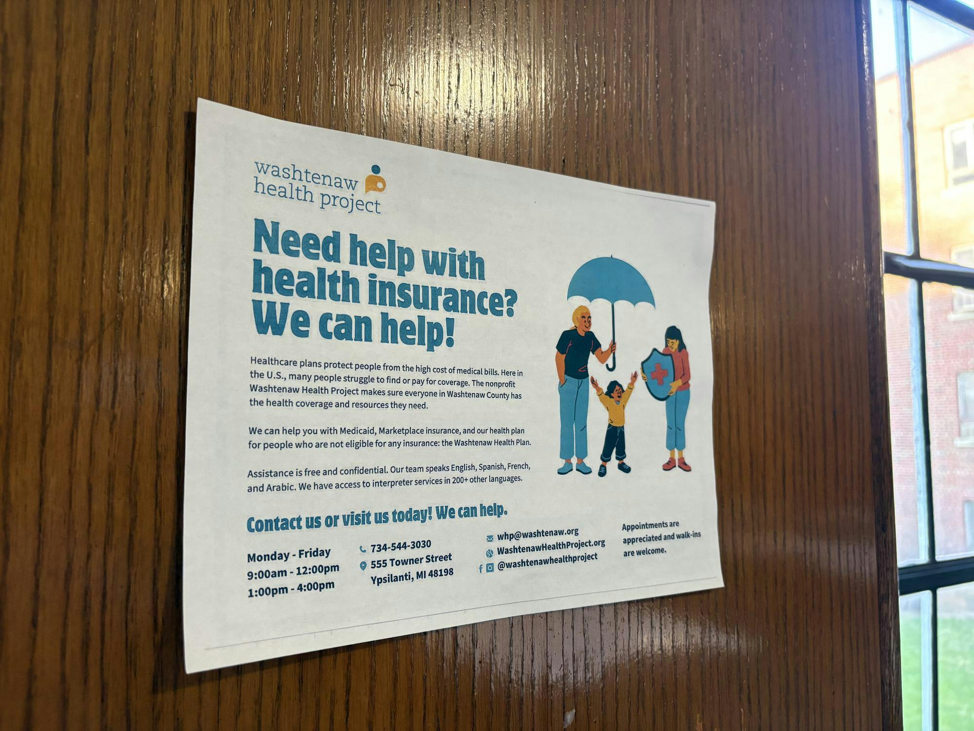 Close-up of a Washtenaw Health Project poster on a wall reading, "Need help with health insurance? We can help!"