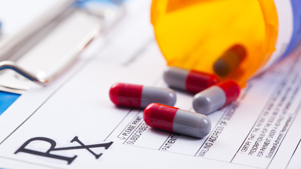 Bottle of prescription drugs laying on RX prescription