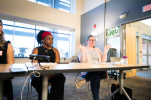 A Black woman with a red headband listens as Cary Bloodworth of the UW Law School.