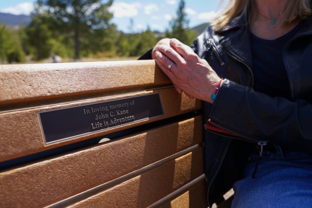 Lauren Brand sits on a memorial bench commemorating her late husband, John Kane, on Tuesday, April 21, 2026, in Frisco. The plaque is a dedication to her husband's adventurous spirit and a playful way of honoring the way he spoke, she said. (Photo by Armando Geneyro/Special to The Colorado Trust)