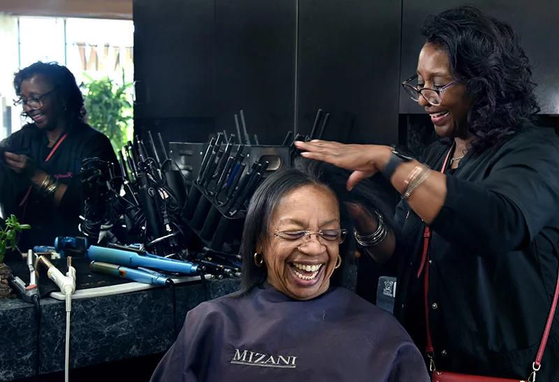 Salon owner Rosalyn Redwine and client Catherine Lewis laugh together. Redwine as been trained by psychologists to offer clients tips on anxiety, depression and more as part of a program that is supporting mental health in Black communities.