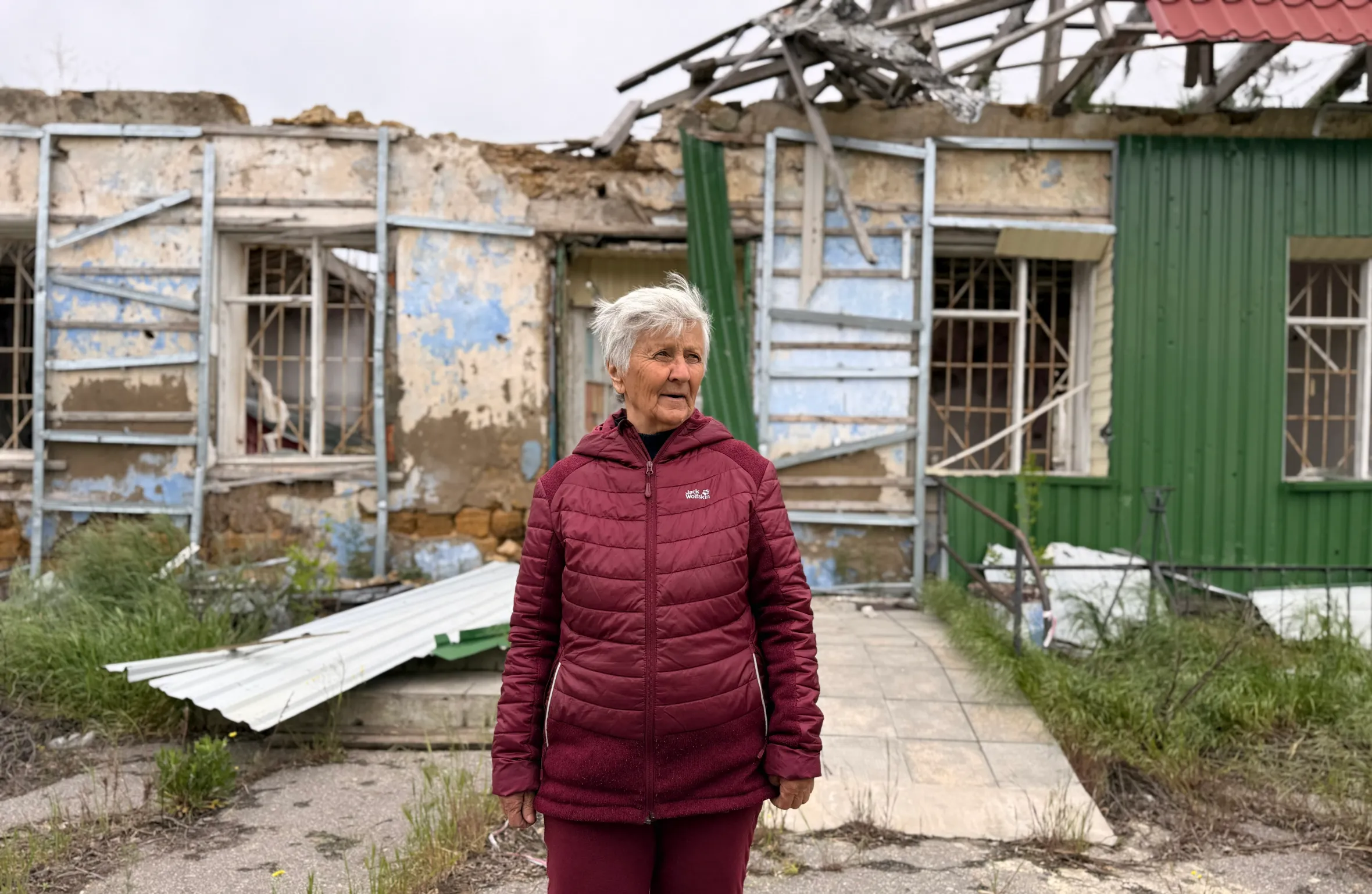 Iryna Volodkovych, a pensioner, stands in front of her damaged home in Ukraine.