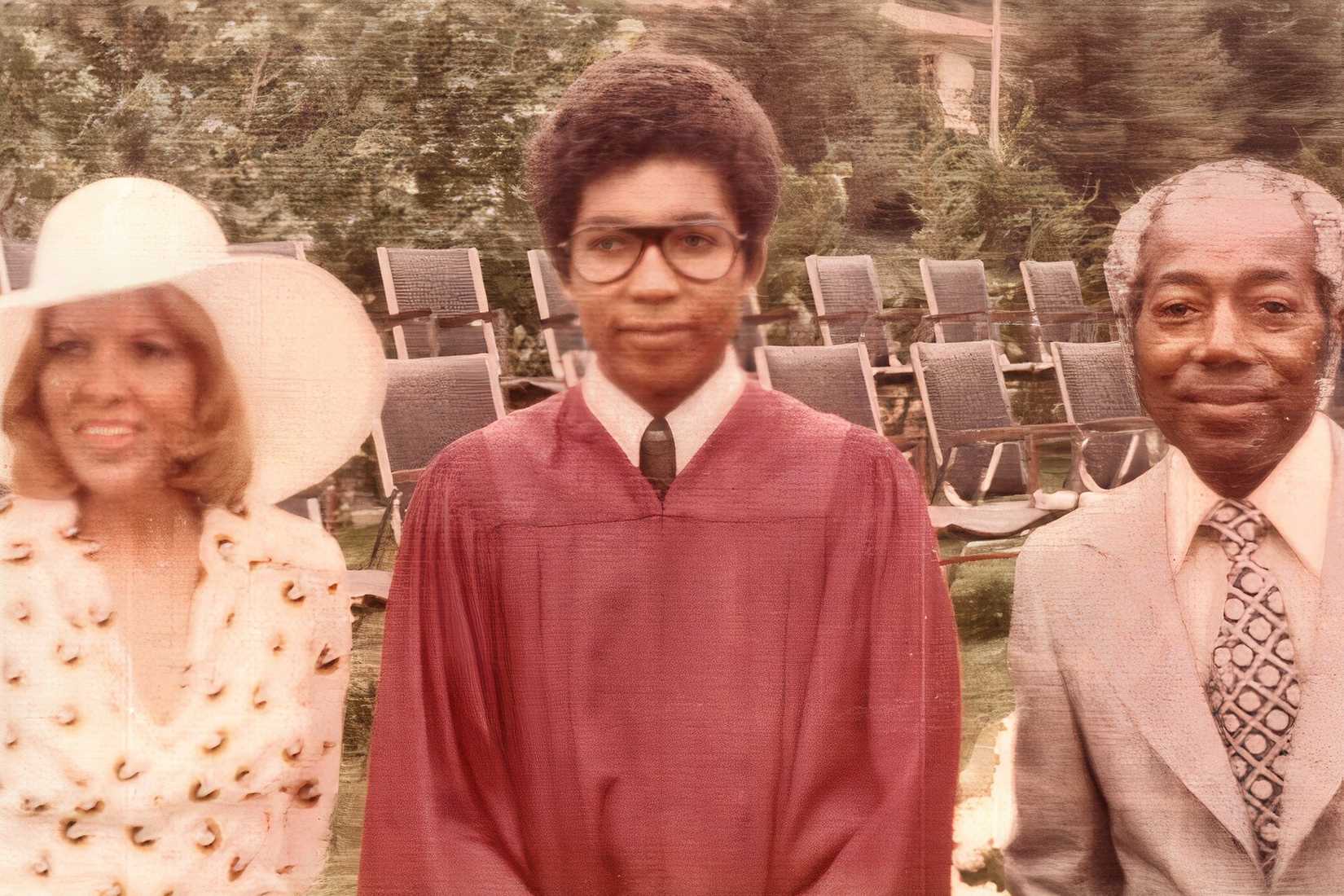 A vintage color photo of student Martin Montague from Fortunate Sons showing him in a red gown standing with his parents.