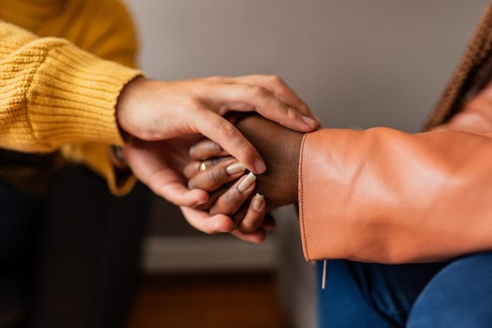 Close-up of therapist holding hands consoling a patient during therapy session