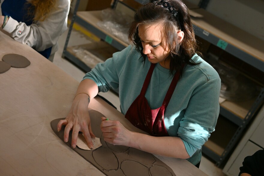 A woman shapes clay during a pottery class