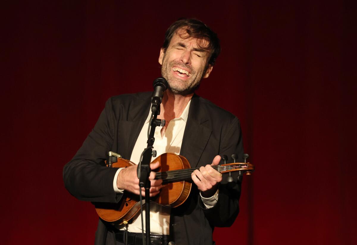 Musician Andrew Bird performs on stage strumming a ukelele