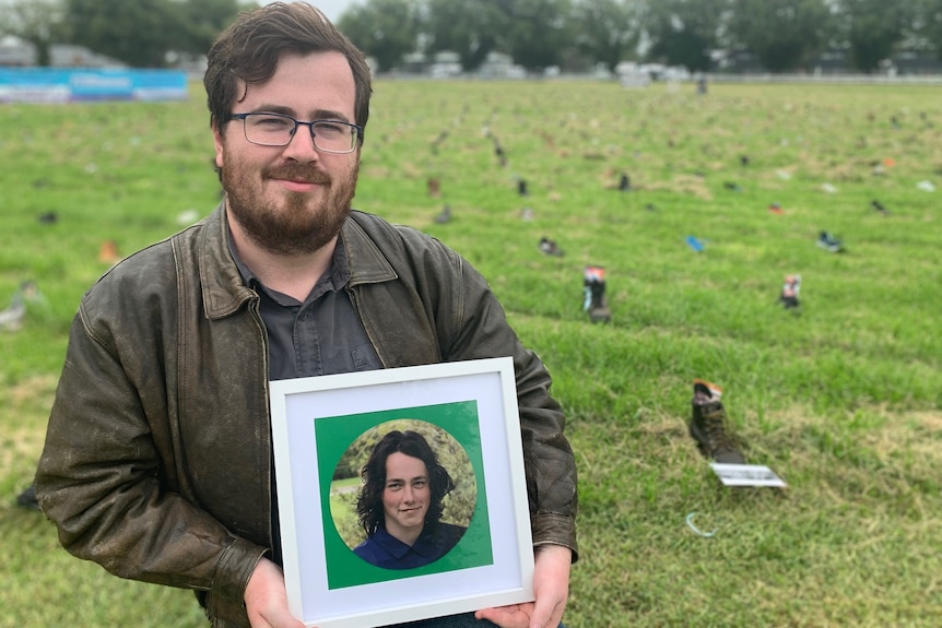 Man holds photo of younger brother.