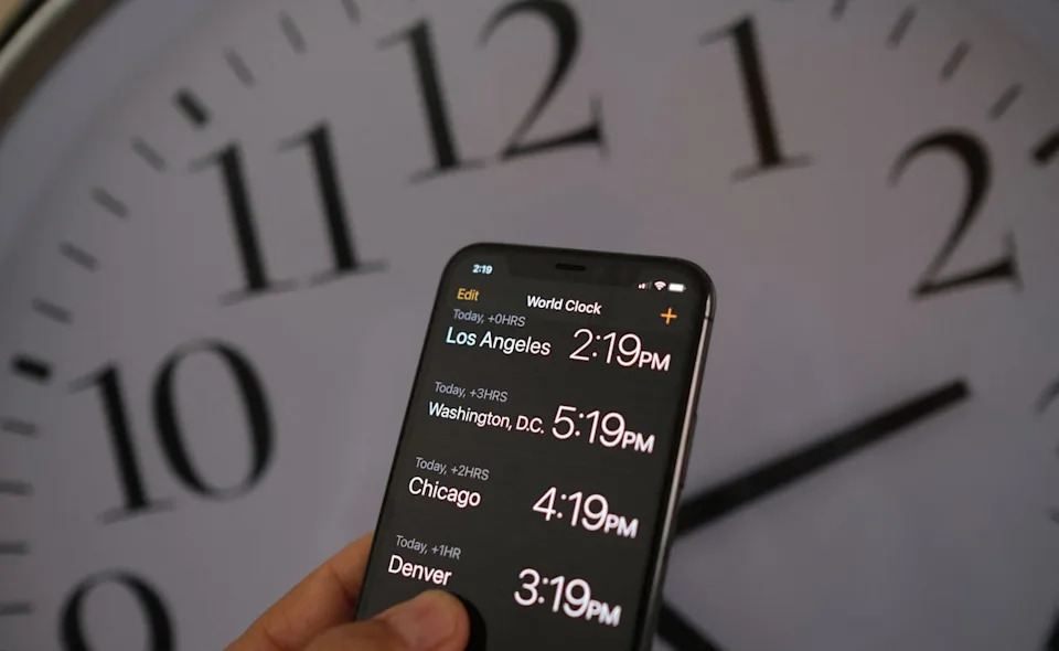 A smartphone showing the time is pictured in front of a clock after the start of daylight saving time (AFP via Getty Images)