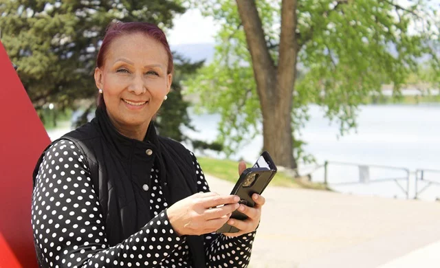 Claudia Rivas, a cancer patient, uses a journaling app on her phone to document her battle against metastatic cancer. Writing helps her process her emotions and find strength. Here, she stands overlooking Lake Loveland from the south shore, a place where she writes and reflects on the beauty around her. Photo by Ana Gretchen Robleto, UCHealth.