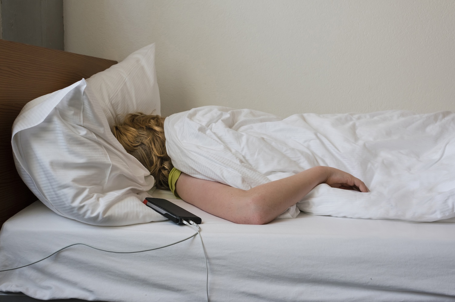 Adolescent teenage boy sleeping in his bed next to smartphone