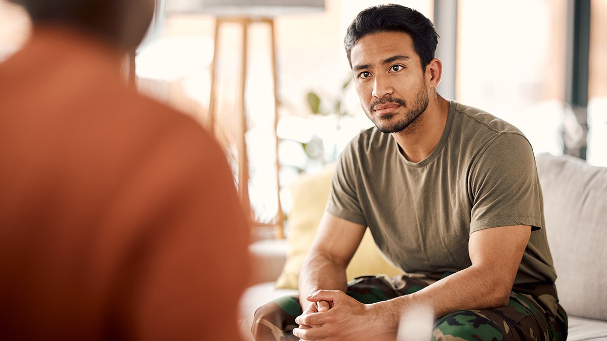 A veteran sitting on a therapist couch talking with a psychologist in a therapy session.