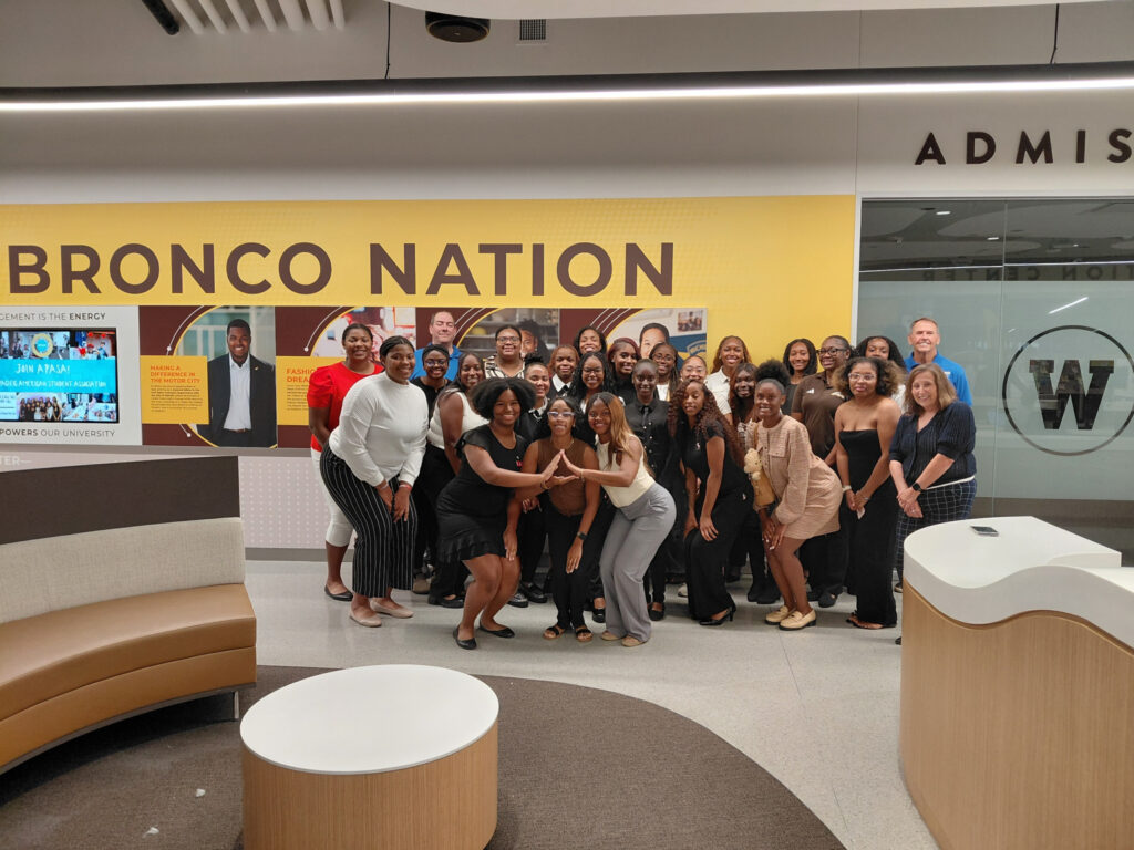 A group of mostly young women pose for a photo in the lobby of a building at Western Michigan University.
