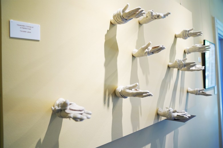 White porcelain hands are mounted to a wall at Peg's Gallery in Hudson. The hands appear to be reaching out to the view with the palms facing upward.
