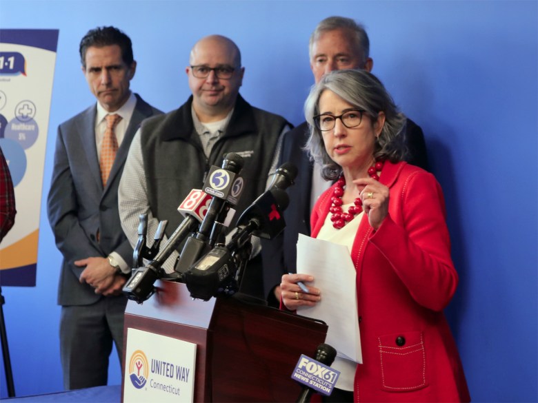 Woman in red jacket speaks at podium