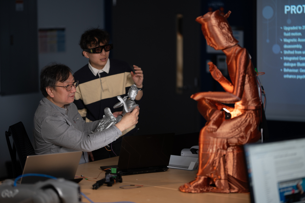 Dr. Patrick Hung, Professor, FBIT, with one of his graduate students, demonstrating the Buddha-inspired mindfulness robot in the Human Machine Lab.