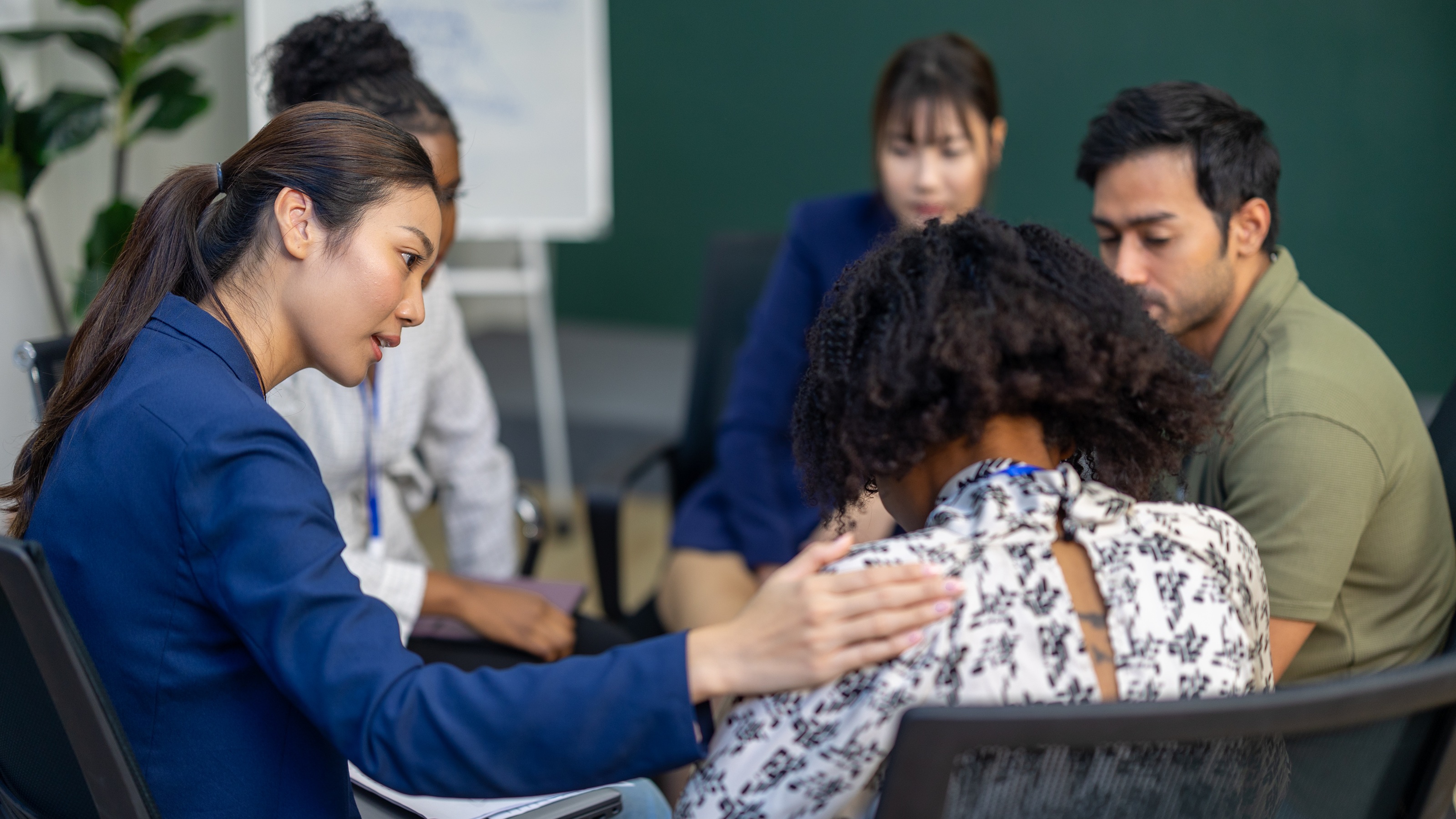 A group therapy session in which one woman is comforting another woman.